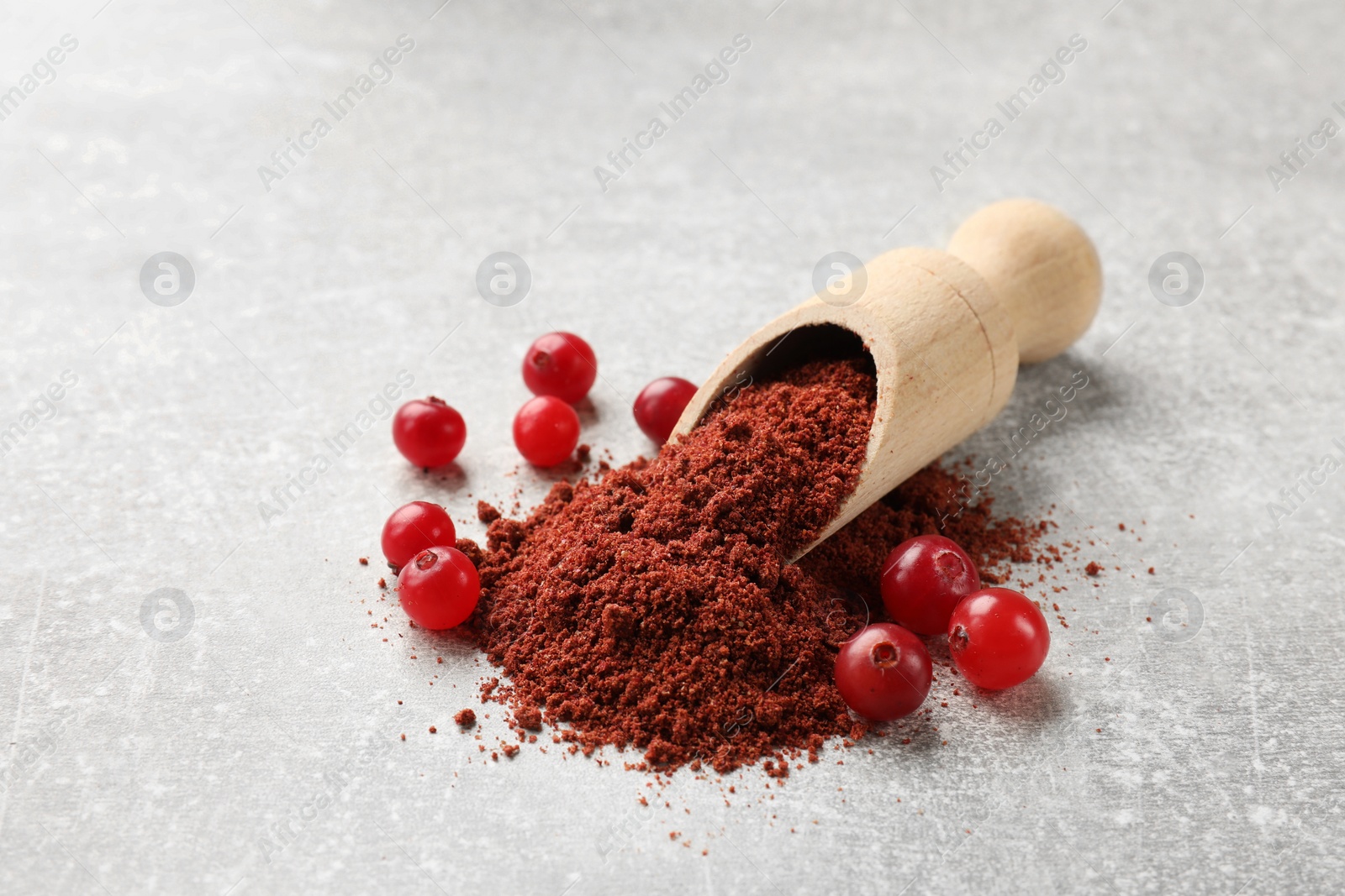 Photo of Pile of cranberry powder, scoop and fresh berries on light grey table. Space for text