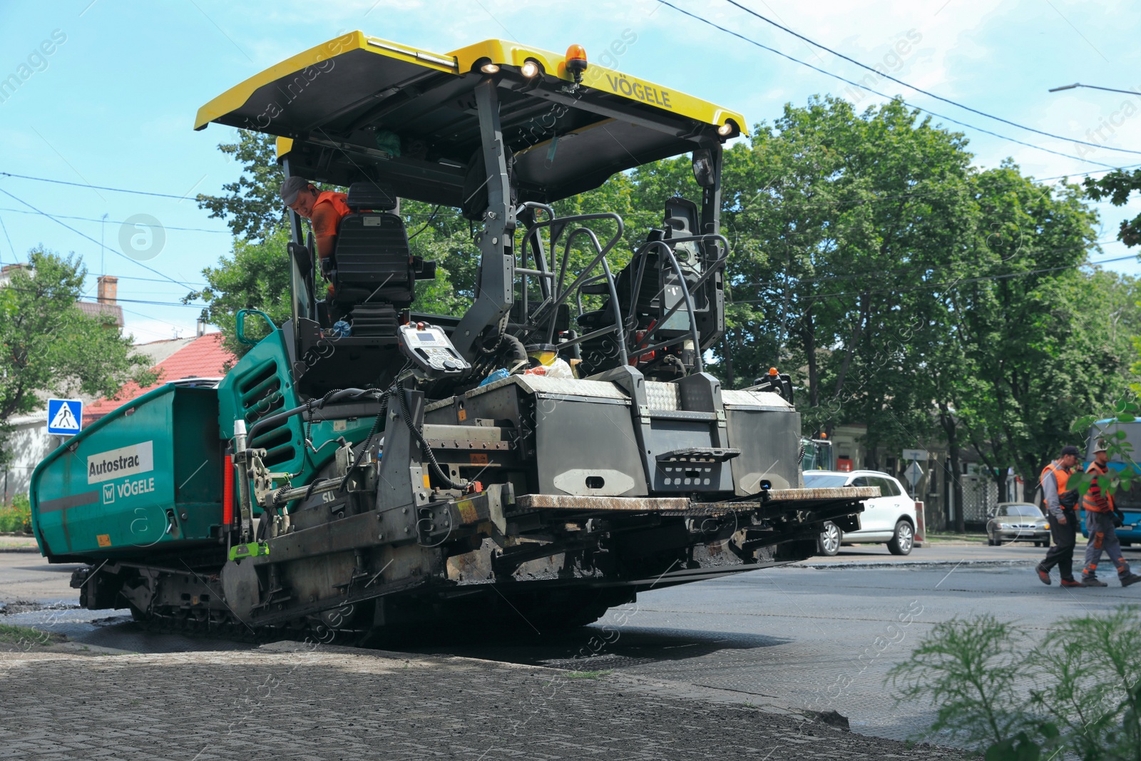 Photo of MYKOLAIV, UKRAINE - AUGUST 04, 2021: Workers with road repair machinery laying new asphalt