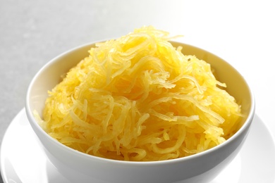 Bowl with cooked spaghetti squash on grey background, closeup