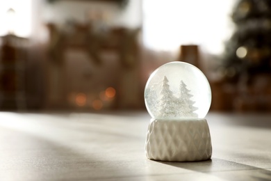 Photo of Snow globe with deer and trees on wooden floor, space for text