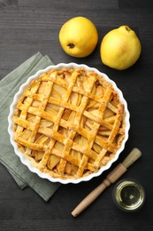 Photo of Tasty homemade quince pie and fresh fruits on black wooden table, flat lay