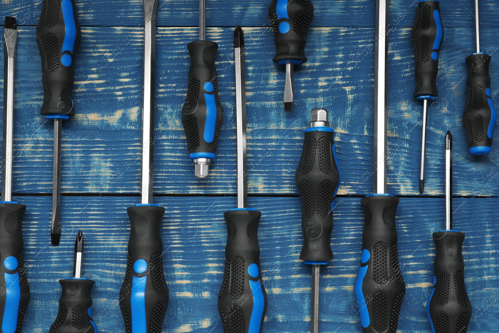 Photo of Set of screwdrivers on blue wooden table, flat lay