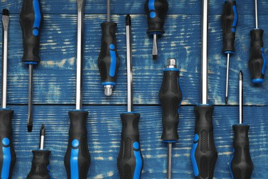 Photo of Set of screwdrivers on blue wooden table, flat lay