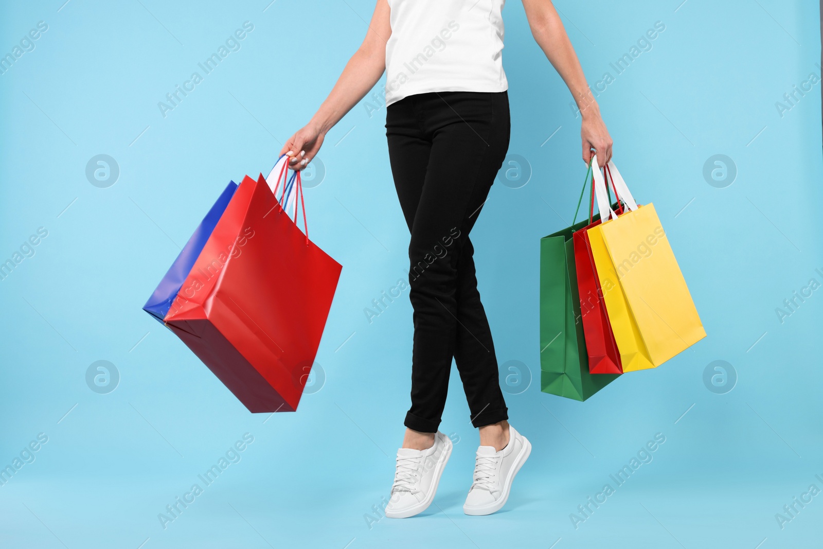 Photo of Woman with shopping bags on light blue background, closeup