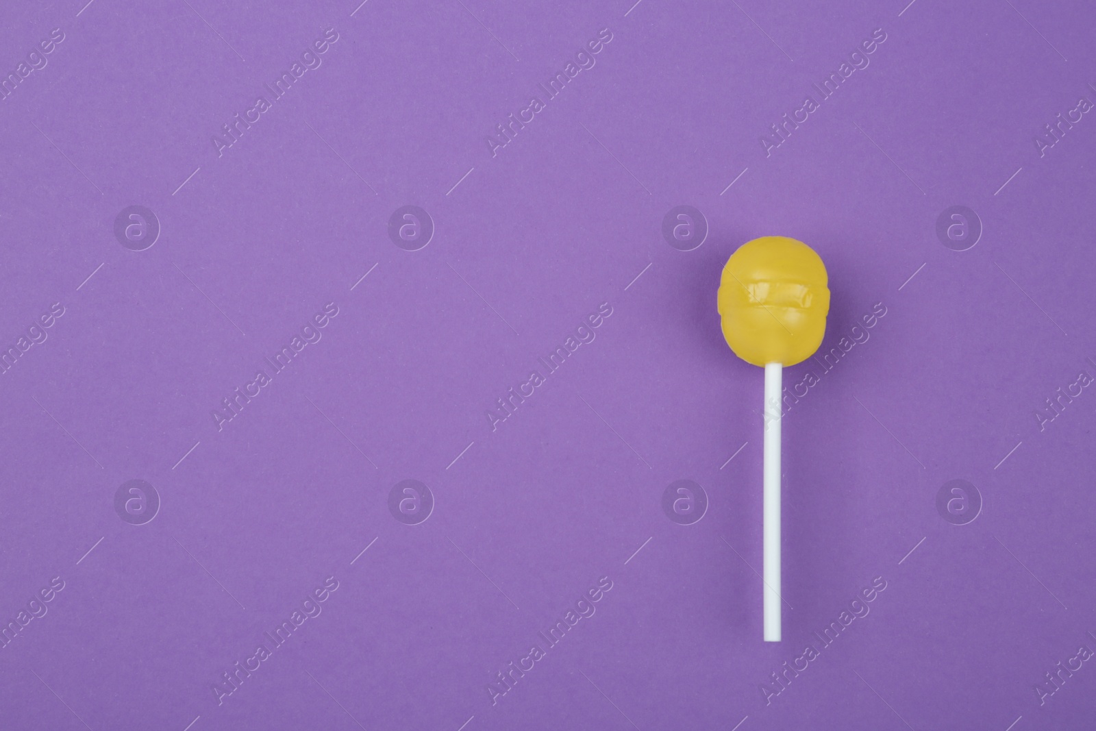 Photo of Tasty lemon lollipop on purple background, top view. Space for text