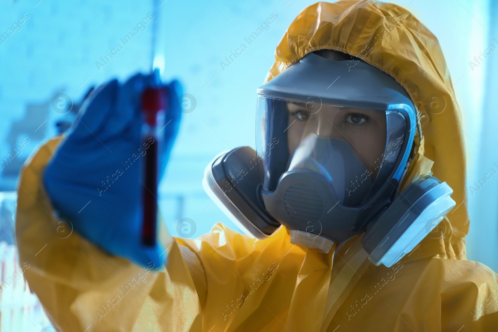 Photo of Scientist in chemical protective suit holding test tube with blood sample at laboratory. Virus research