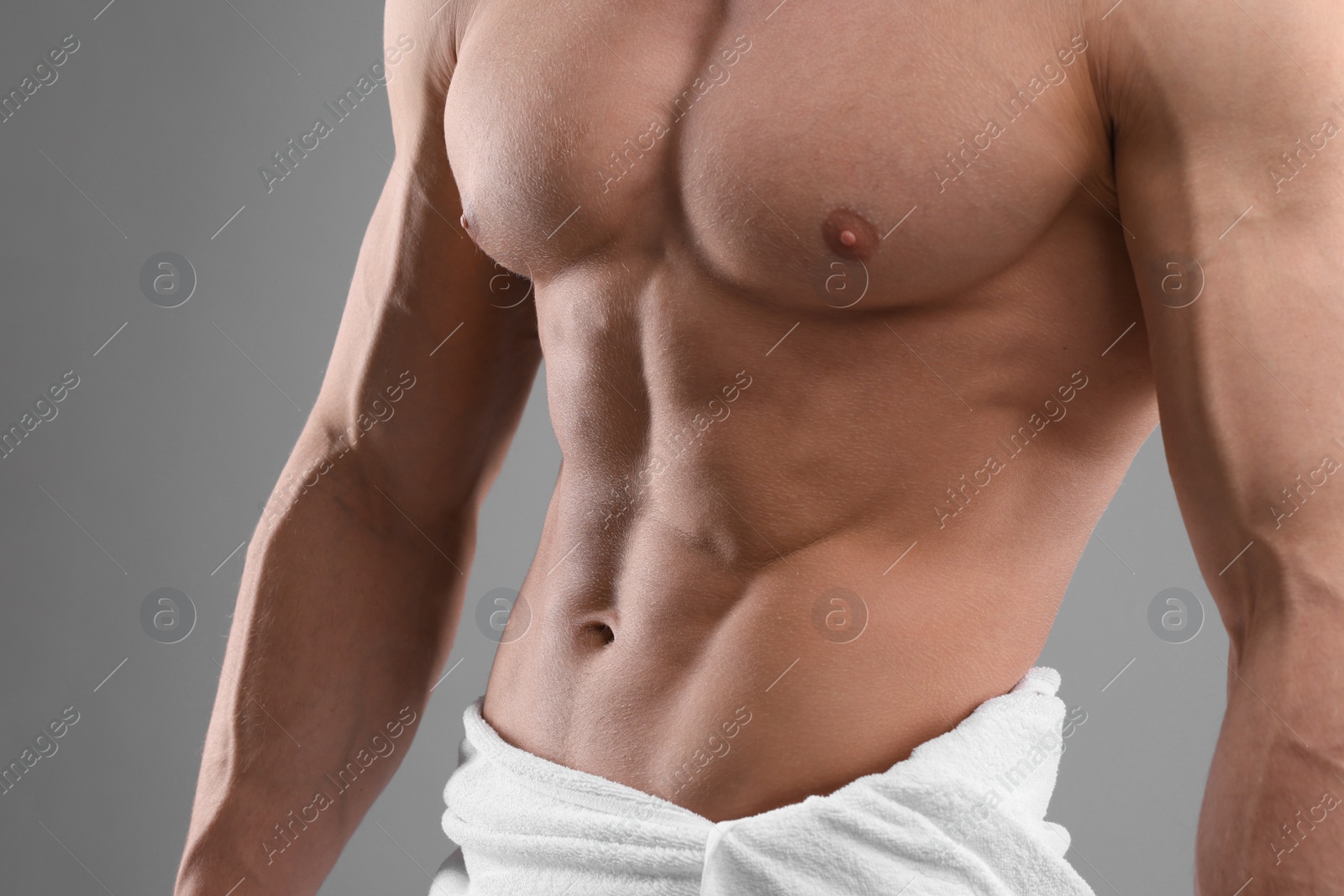 Photo of Muscular man showing abs on grey background, closeup