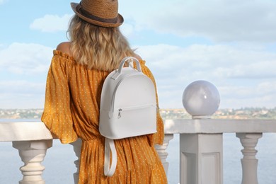 Photo of Young woman with stylish backpack outdoors, back view