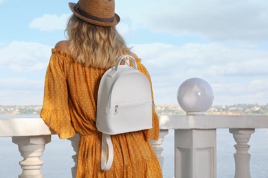 Young woman with stylish backpack outdoors, back view