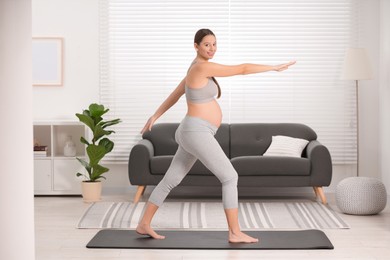 Pregnant woman doing exercises on yoga mat at home