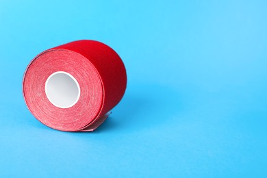 Photo of Red kinesio tape in roll on light blue background. Space for text