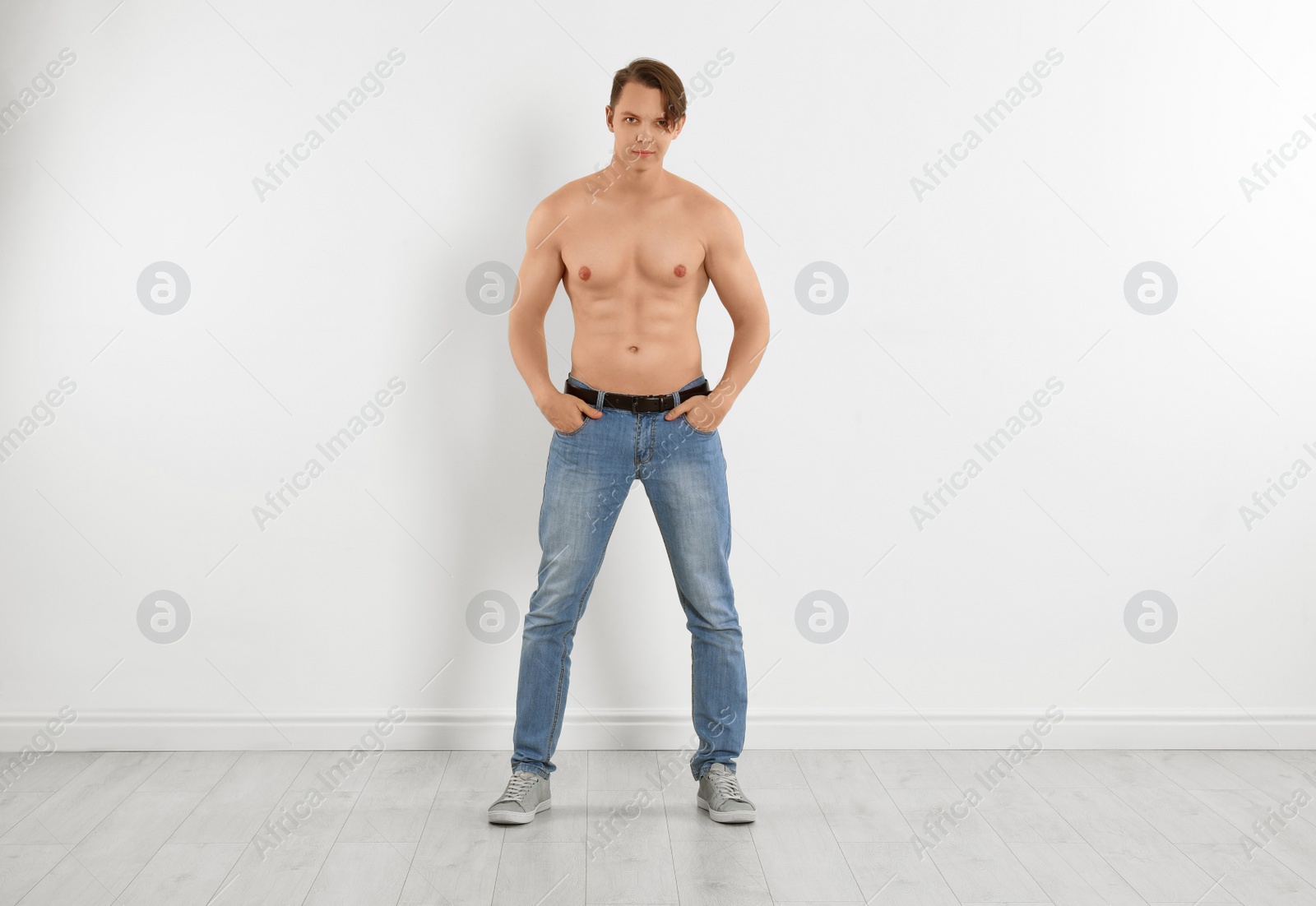 Photo of Young man in stylish jeans near white wall