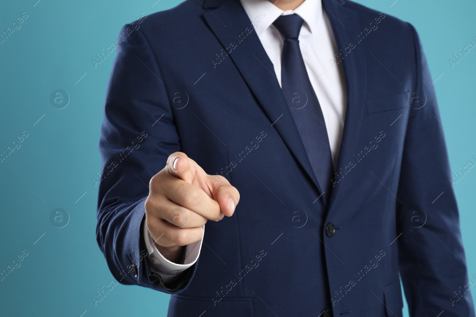 Photo of Businessman touching something on light blue background, closeup. Finger gesture