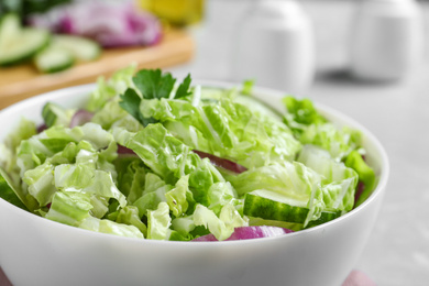 Photo of Tasty salad with cabbage and cucumbers on light grey table, closeup