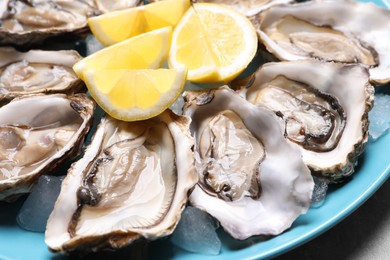 Photo of Fresh oysters with lemon on plate, closeup