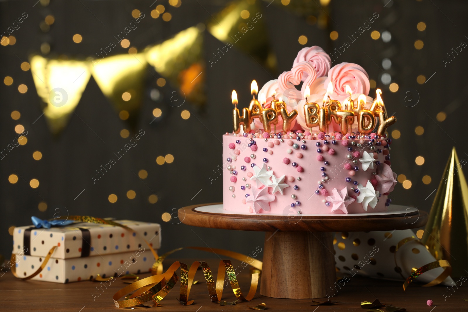 Photo of Beautiful birthday cake with burning candles and decor on wooden table. Space for text