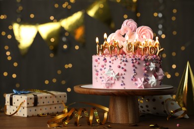 Photo of Beautiful birthday cake with burning candles and decor on wooden table. Space for text