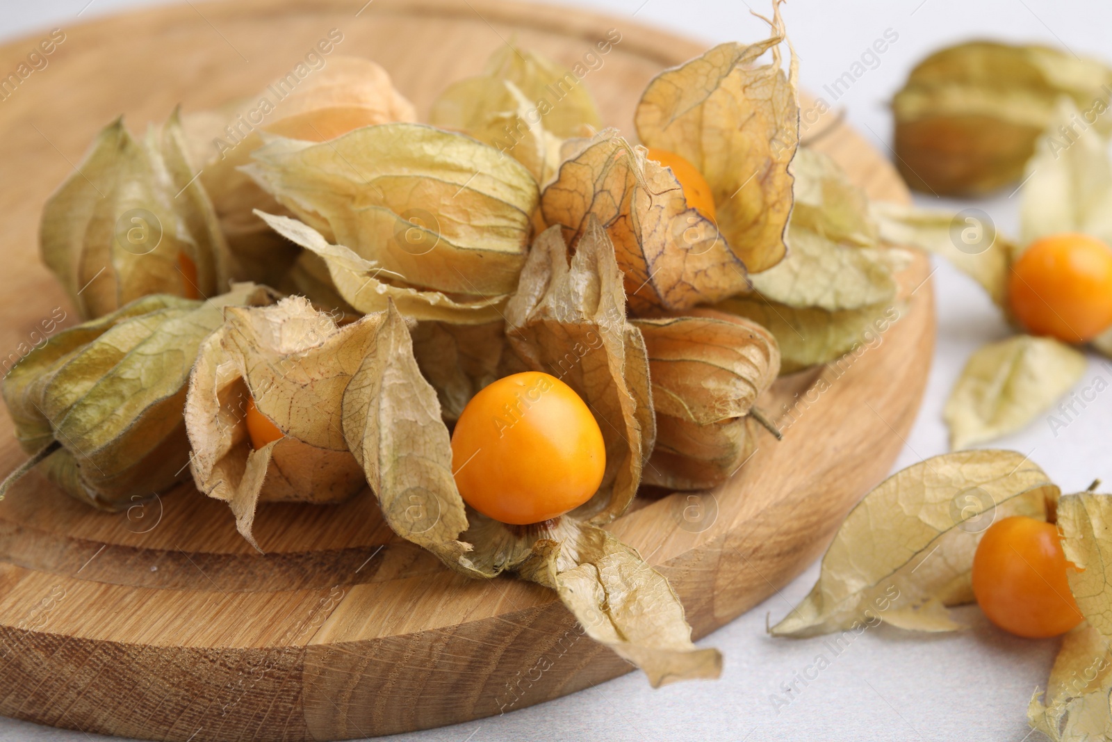 Photo of Ripe physalis fruits with calyxes on white table, closeup