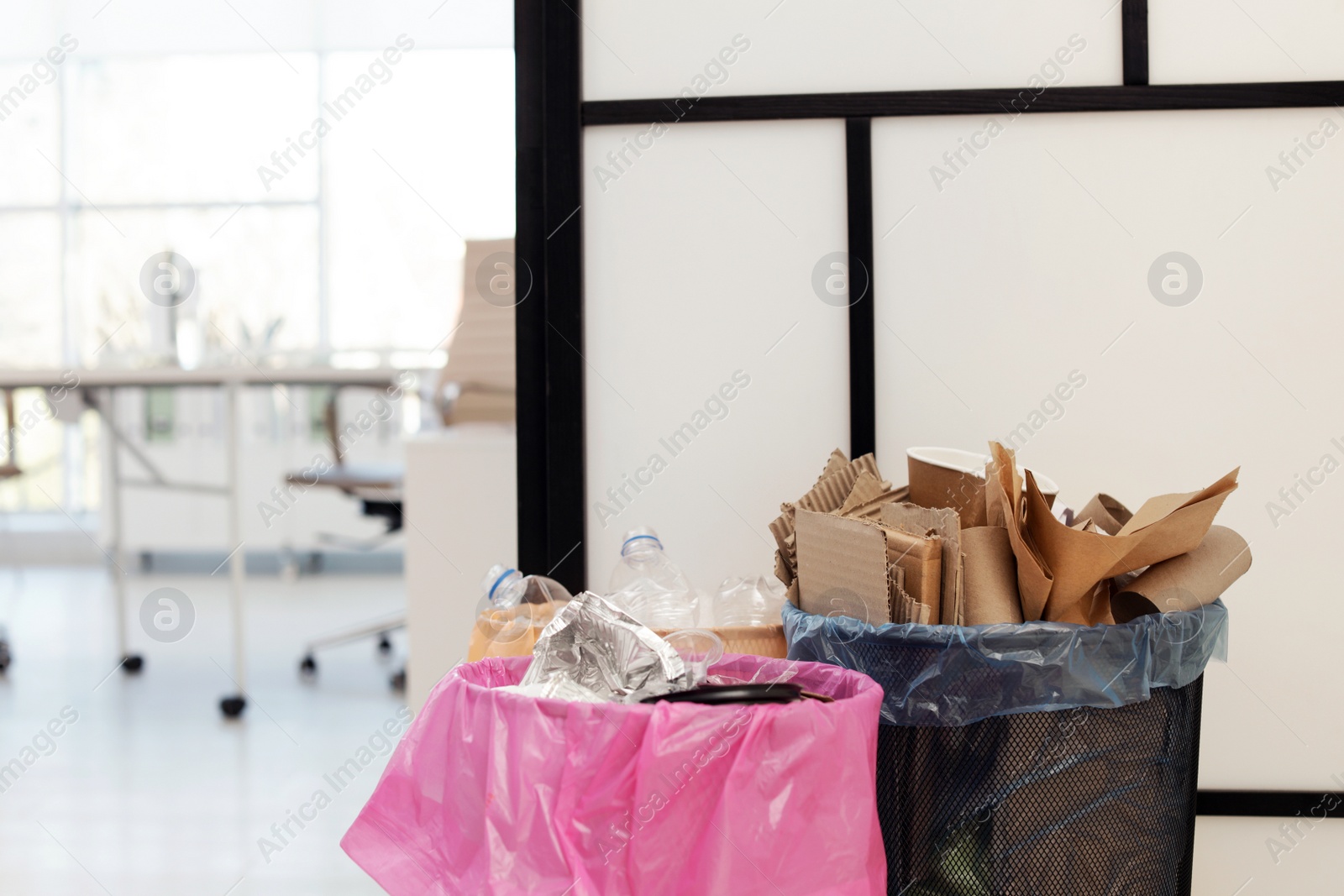 Photo of Full trash cans in modern office, space for text. Waste recycling