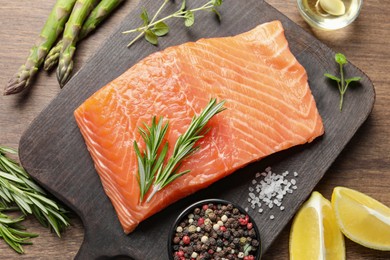 Fresh raw salmon and ingredients for marinade on wooden table, flat lay