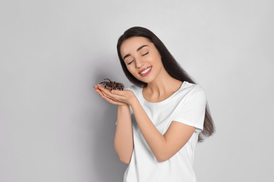 Photo of Woman holding striped knee tarantula on light background. Exotic pet