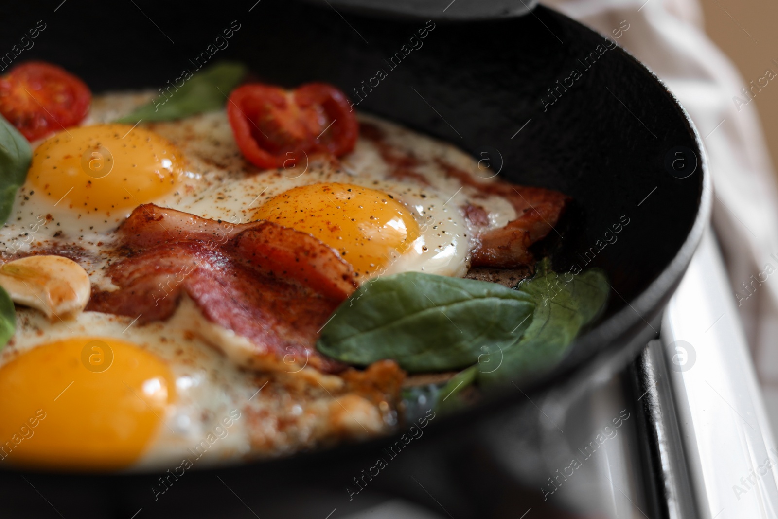 Photo of Delicious fried eggs with bacon and tomatoes in pan, closeup