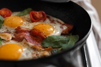 Photo of Delicious fried eggs with bacon and tomatoes in pan, closeup