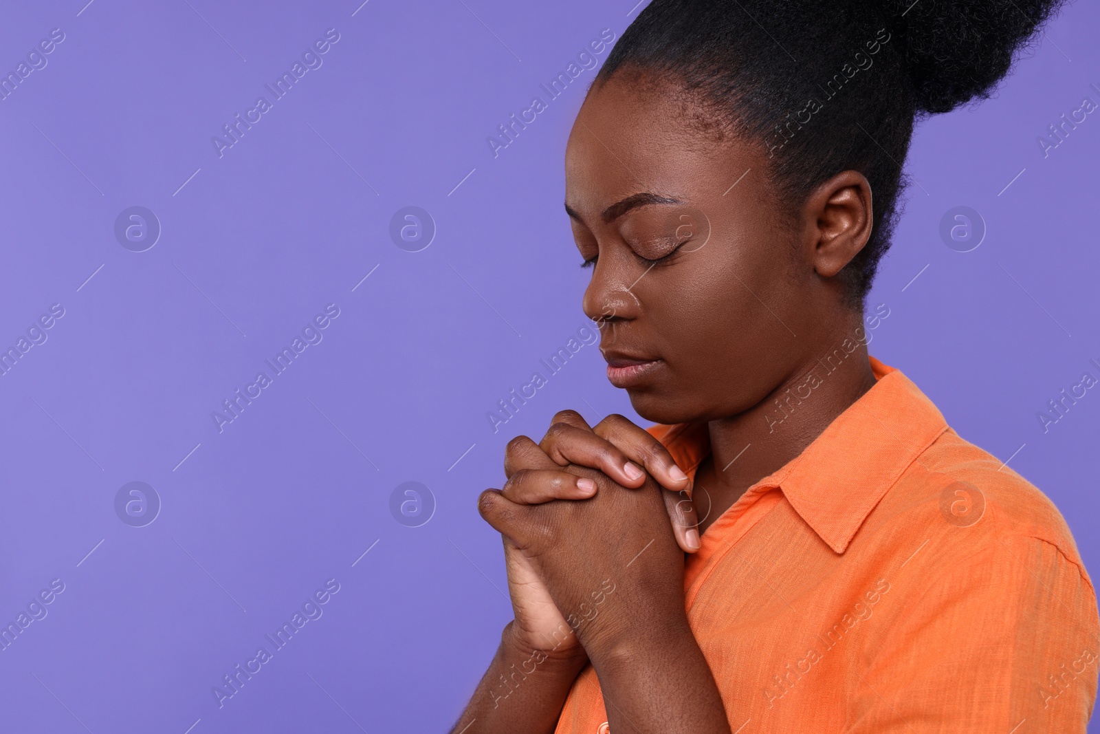 Photo of Woman with clasped hands praying to God on purple background. Space for text