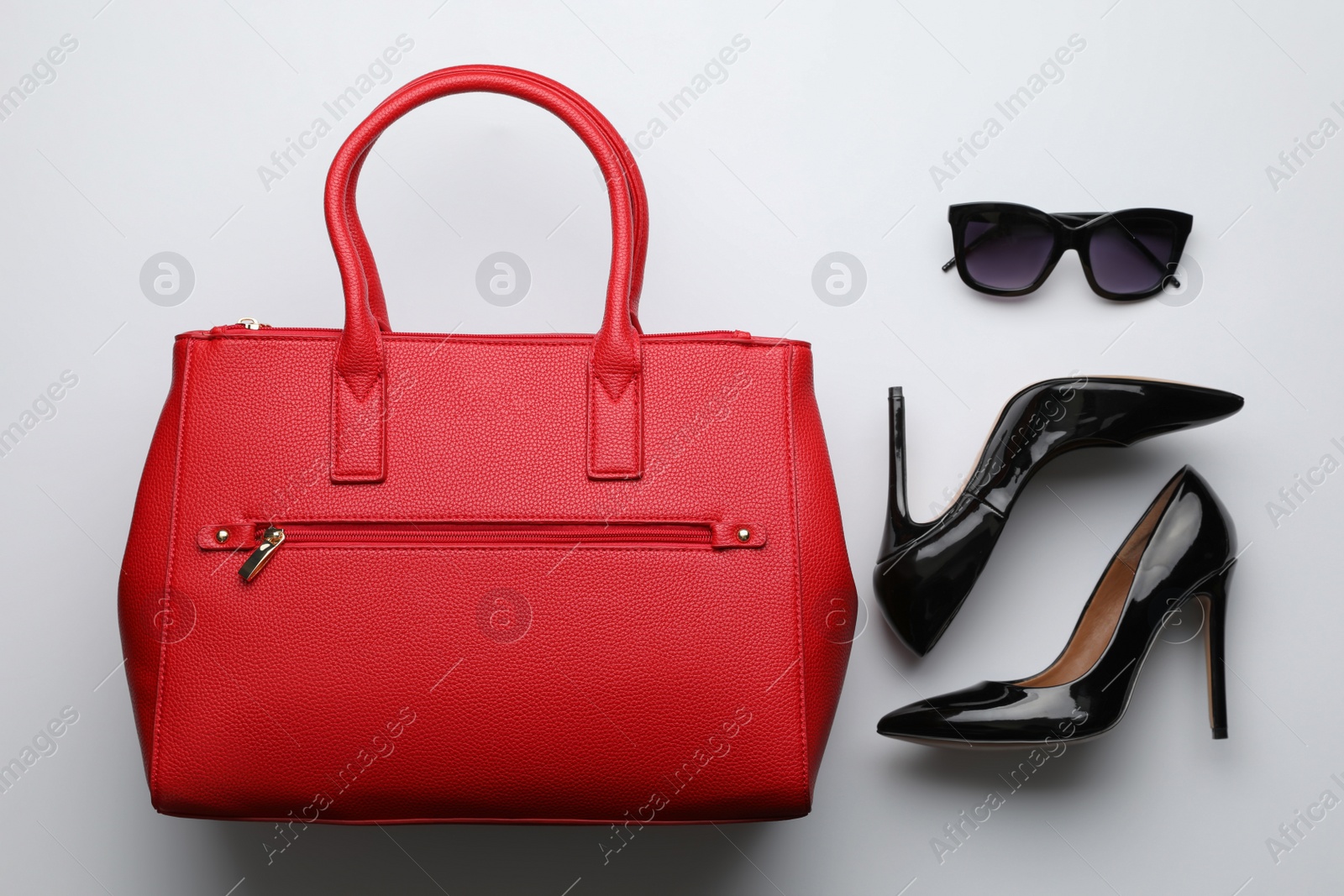 Photo of Stylish woman's bag, sunglasses and shoes on light background, flat lay