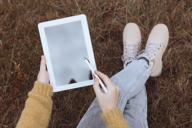 Photo of Top view of young woman drawing with graphic tablet outdoors, closeup
