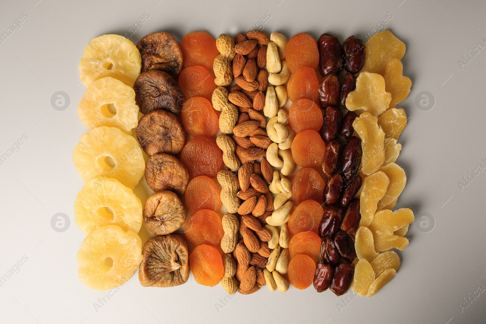 Photo of Different tasty nuts and dried fruits on beige background, flat lay