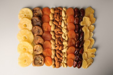 Different tasty nuts and dried fruits on beige background, flat lay