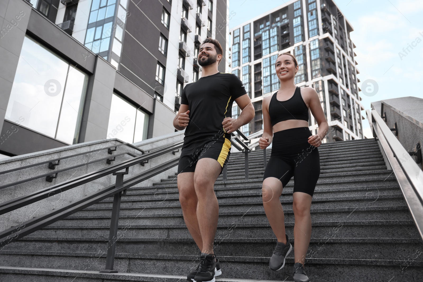 Photo of Healthy lifestyle. Happy couple running on steps outdoors, low angle view