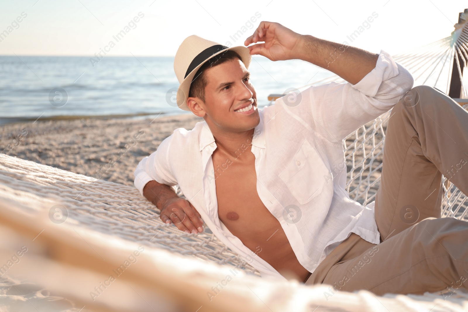 Photo of Man relaxing in hammock on beach. Summer vacation