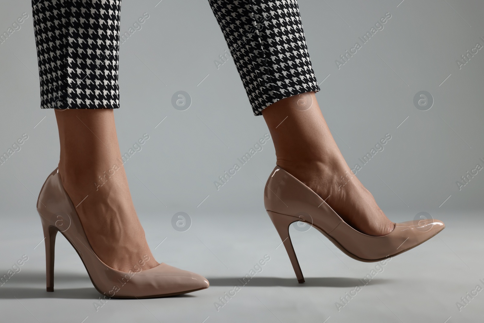 Photo of Businesswoman in beige shoes on grey background, closeup