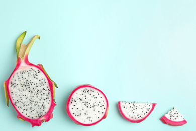 Photo of Delicious cut dragon fruit (pitahaya) on light blue background, flat lay. Space for text