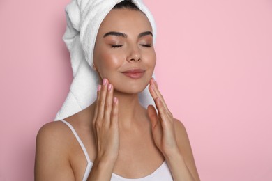 Beautiful young woman with towel on head against pink background