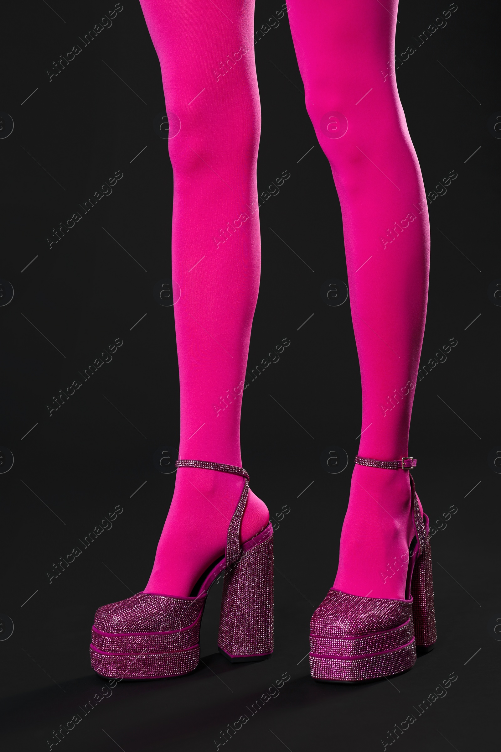 Photo of Woman wearing pink tights and high heeled shoes with platform and square toes on dark grey background, closeup