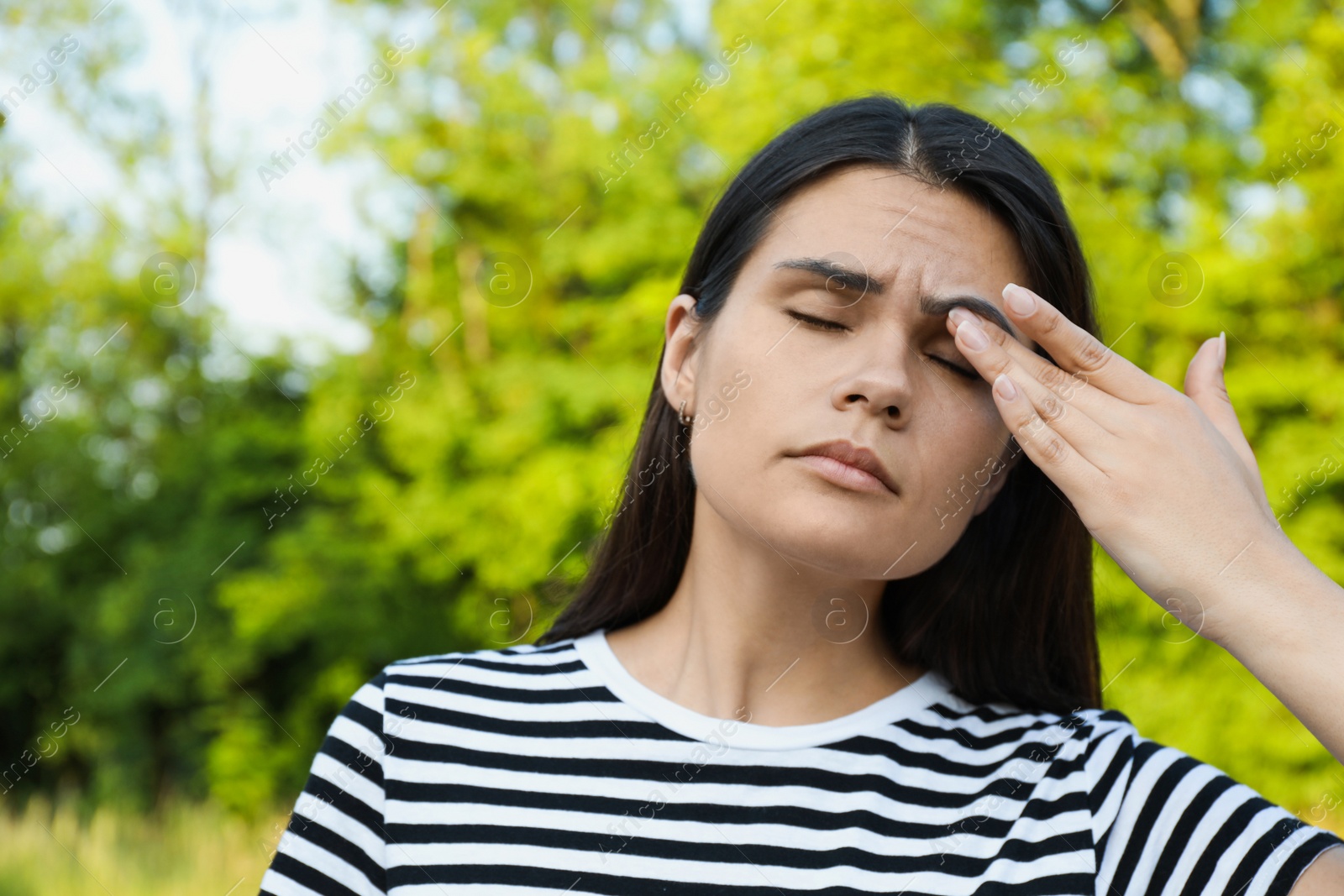 Photo of Young woman suffering from eyestrain outdoors on sunny day