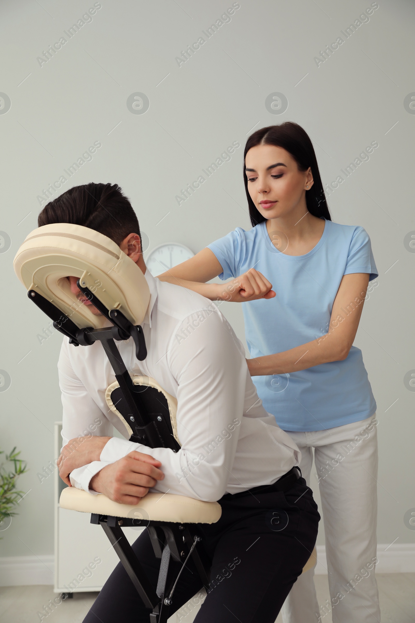 Photo of Man receiving massage in modern chair indoors