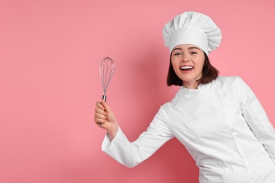 Photo of Happy confectioner with whisk on pink background, space for text