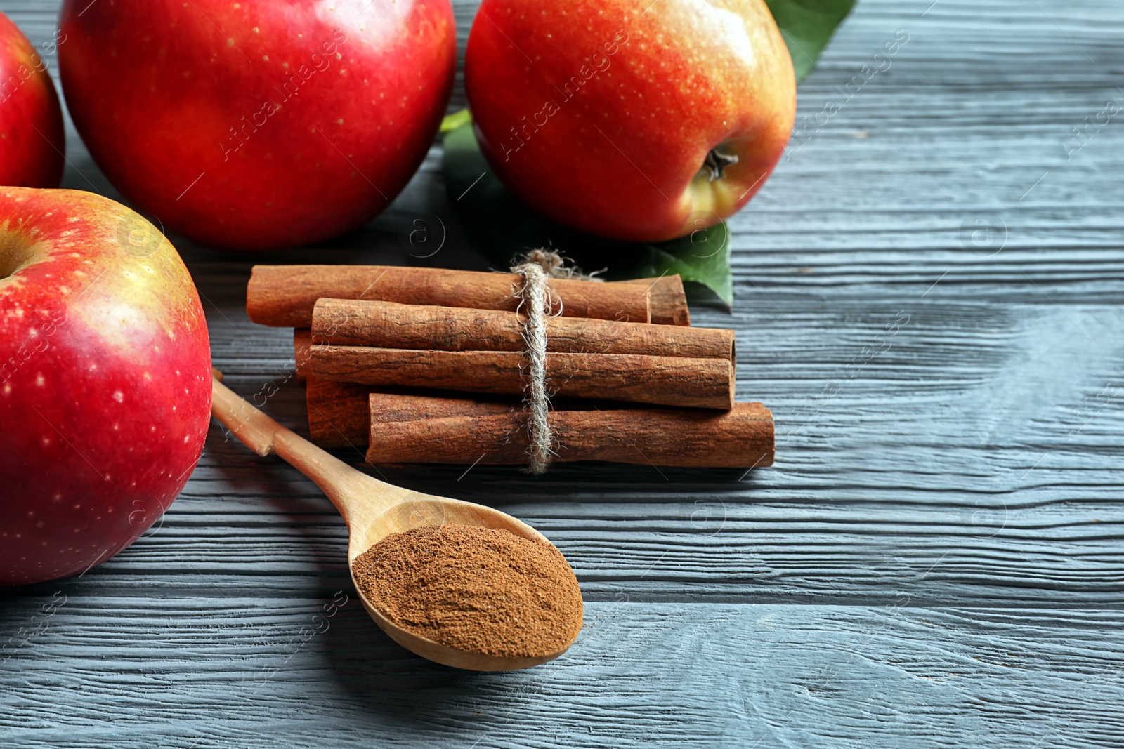 Photo of Fresh apples with cinnamon sticks and powder on wooden table