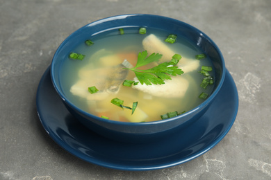 Photo of Delicious fish soup in bowl on grey table, closeup