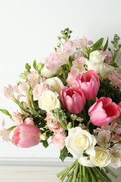 Beautiful bouquet of fresh flowers on table near white wall