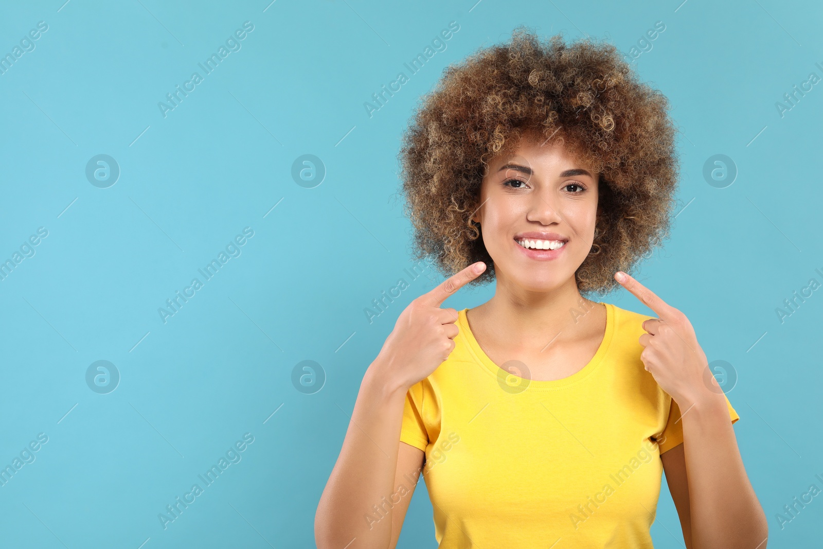 Photo of Woman showing her clean teeth and smiling on light blue background, space for text