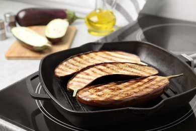Photo of Delicious grilled eggplant halves in pan on stove, closeup
