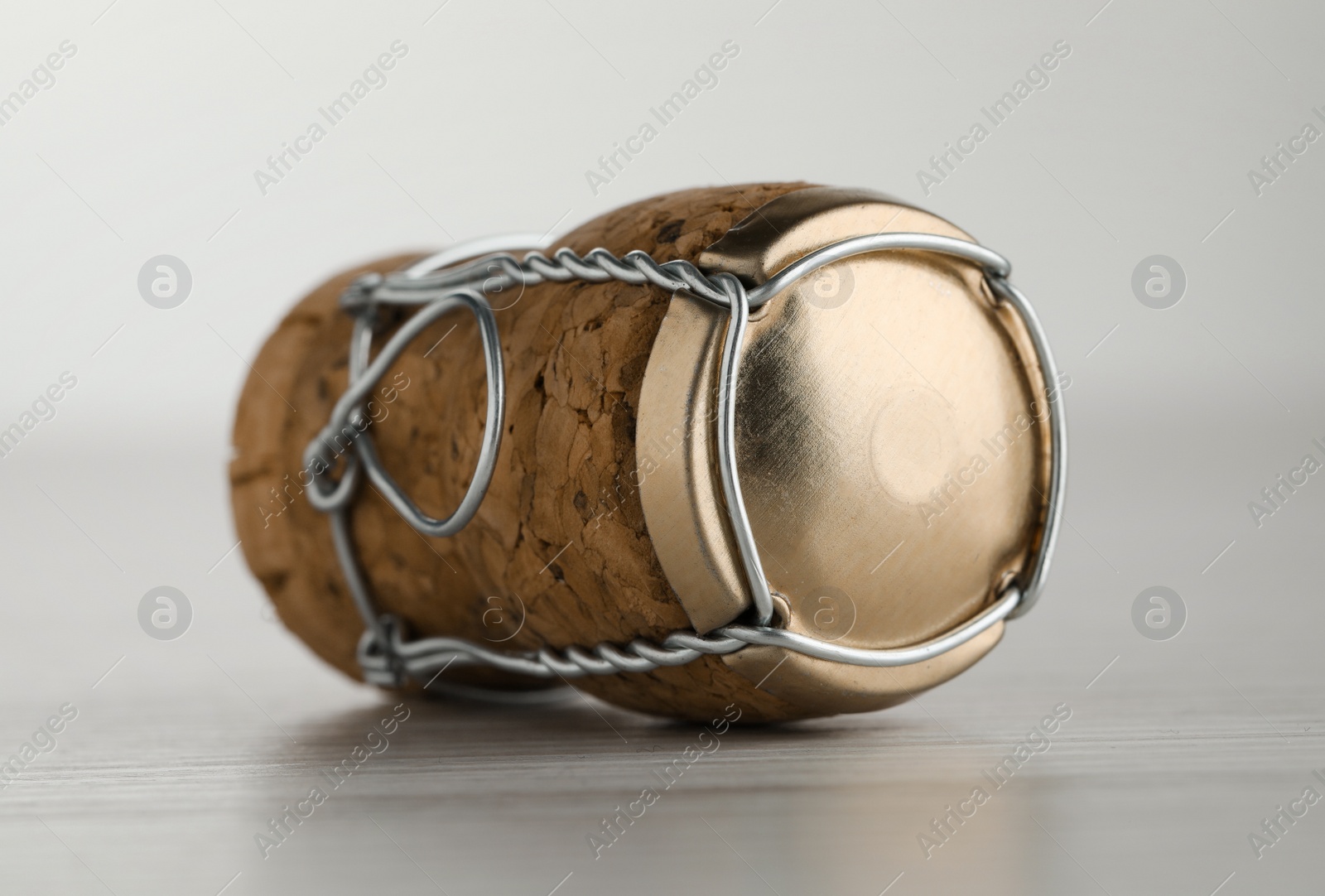 Photo of Cork of sparkling wine and muselet cap on white wooden table, closeup