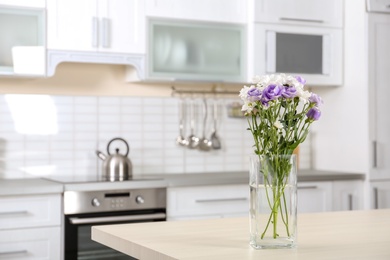 Photo of Vase with beautiful flowers on table in kitchen interior. Space for text