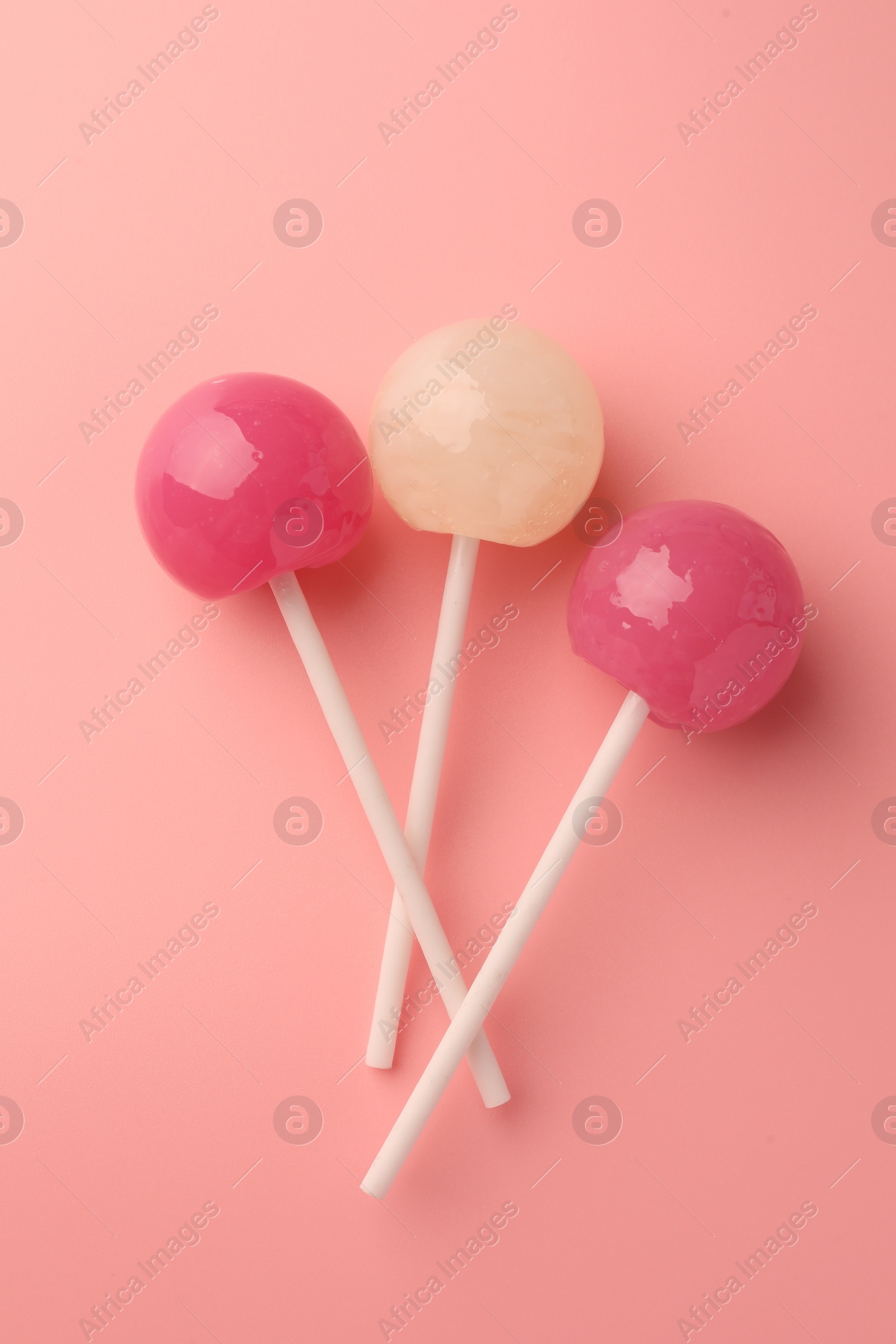 Photo of Tasty lollipops on pink background, flat lay