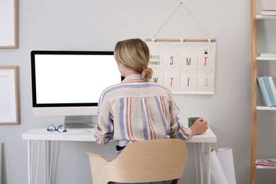Photo of Young woman working on computer at table in room